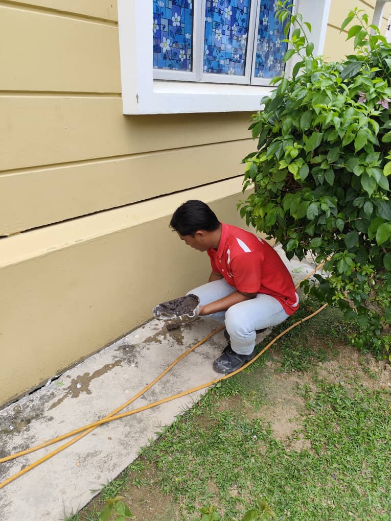 GPC technician inspecting soil near a house foundation